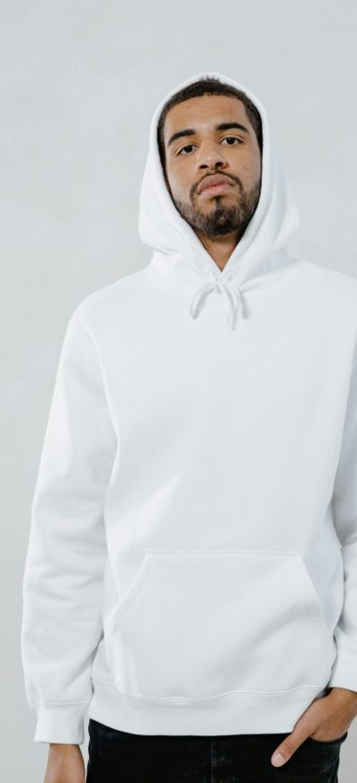 Man in casual white hoodie standing against a neutral background, suitable for lifestyle imagery.
